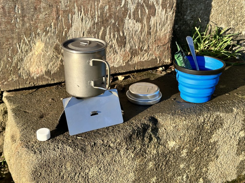 Alpkit MiTiMug with lid, collapsible 400ml Sea-to-Summit mug, multi-fuel bushcraft stove, coffee bag, Trangia tin for solid fuel tablets.