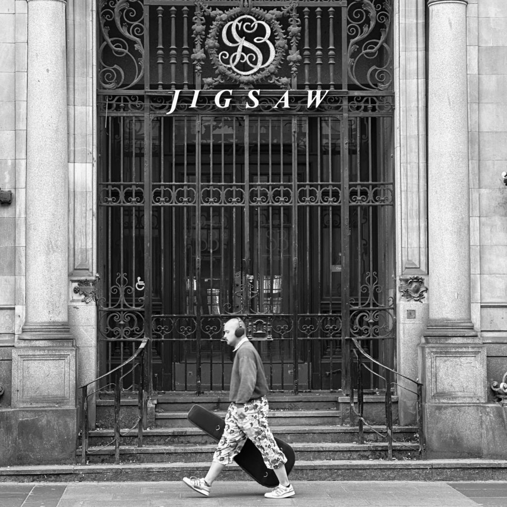 Musician walking past iron gates
